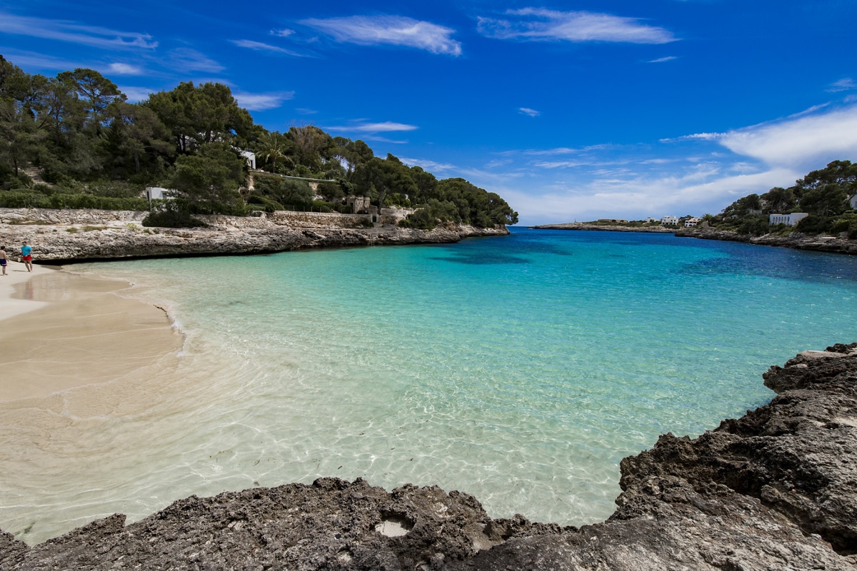 Strand Cala d'Or - schöner Strand umgeben von Felsen und einem Pinienwald im Südosten Mallorcas
