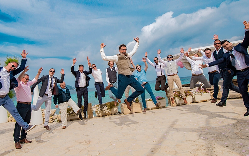 Brautpaar und Hochzeitsgäste springen gemeinsam am Strand