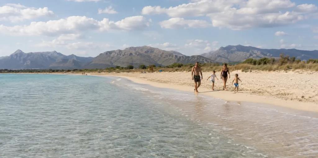 Familie mit zwei Kindern an einem flach abfallenden Sandstrand im Norden Mallorcas