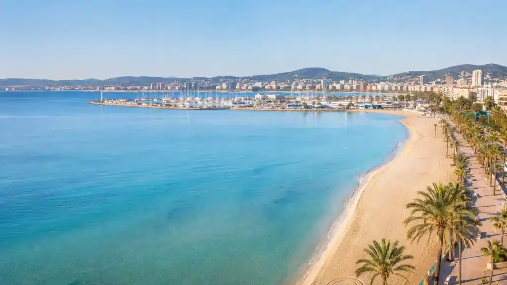 Sandstrand mit Blick auf Hafen und Küstenlinie in S’Arenal auf Mallorca