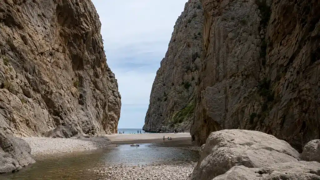 Hohe Felswände und Kiesstrand am Ausgang des Torrent de Pareis bei Sa Calobra