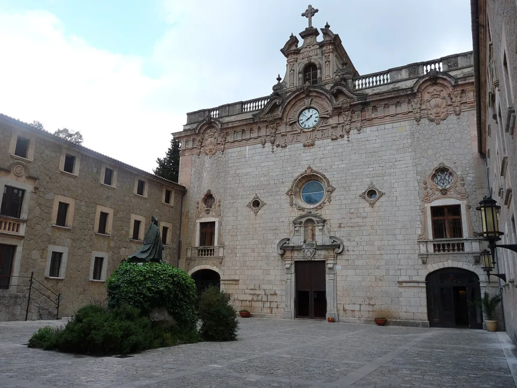 Fassade der Basilika im Santuari de Lluc zwischen Klostergebäuden und Bäumen